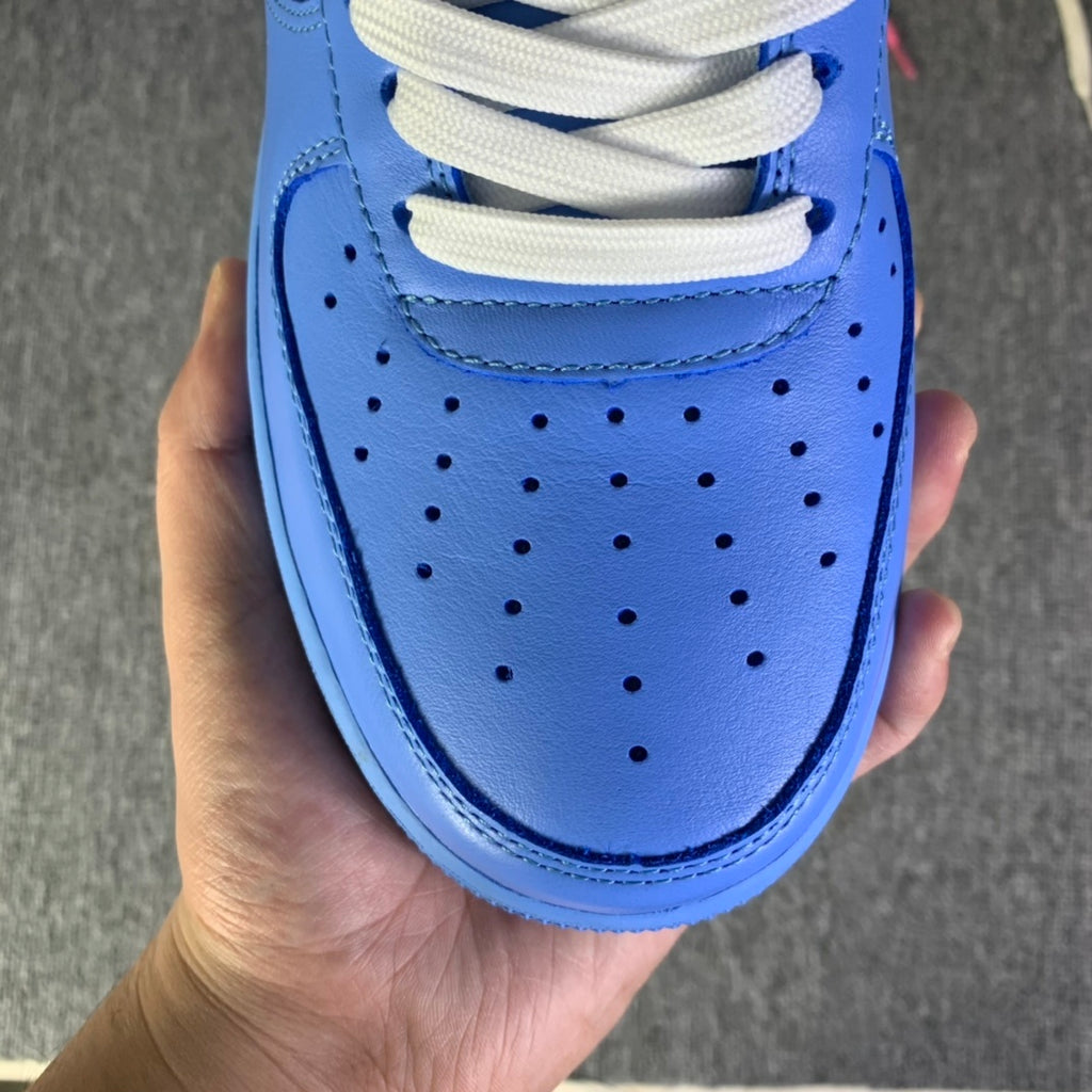 Blue leather sneaker toe with perforations, white laces, held in hand