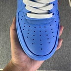 Blue leather sneaker toe with perforations, white laces, held in hand