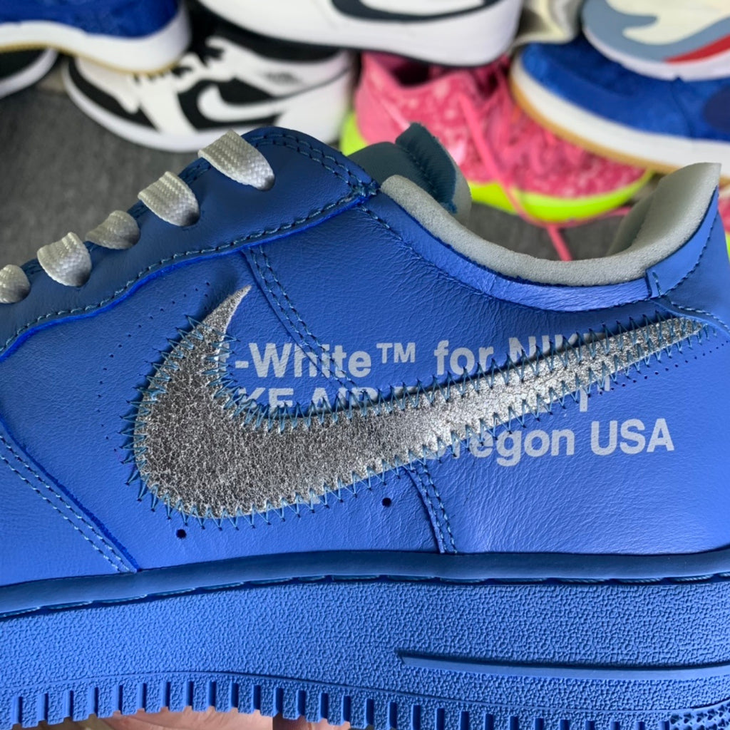 Blue sneaker side close-up with grey swoosh detail and White TM text