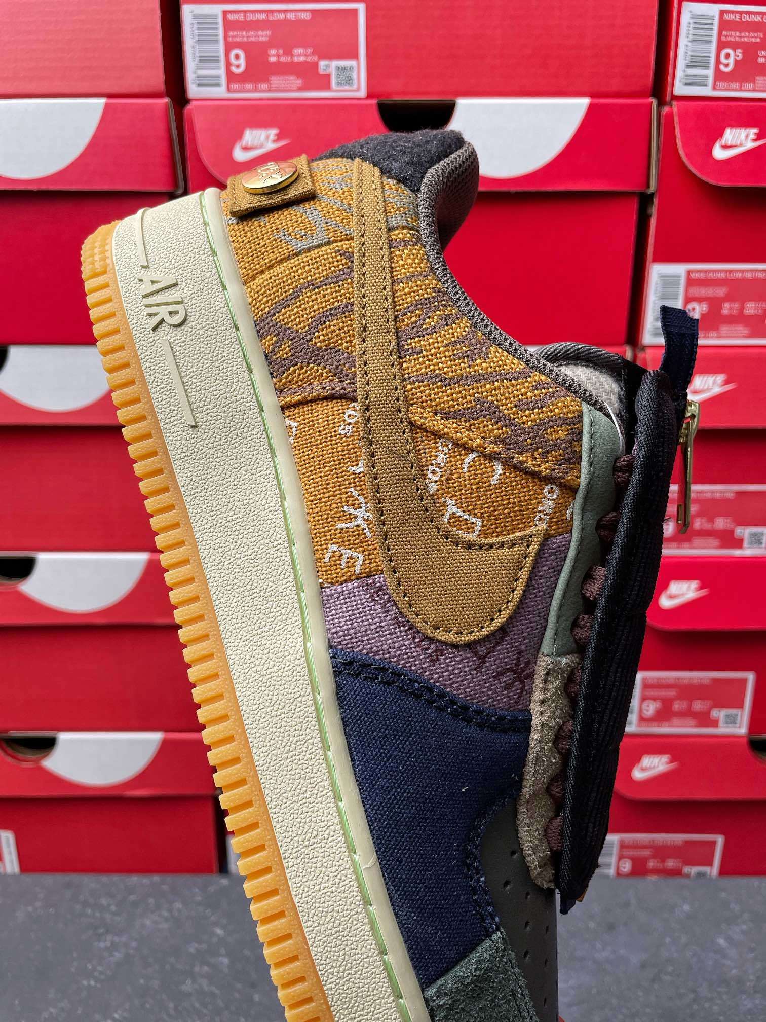 Low-top sneaker with brown suede heel patch, navy toe panel, and dark laces