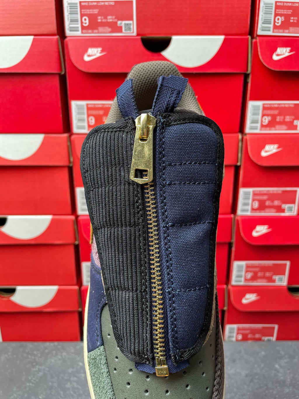 Low-top sneaker back view with dark navy fabric, tan midsole, and gold zipper pull