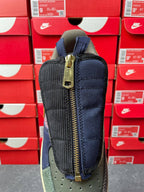 Low-top sneaker back view with dark navy fabric, tan midsole, and gold zipper pull