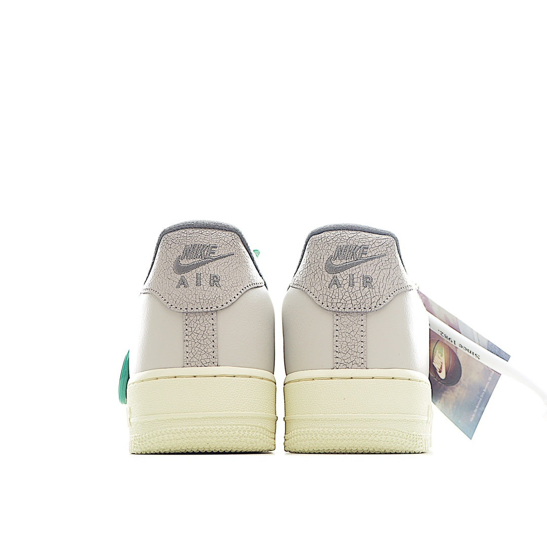 White Nike Air Force 1 sneakers with Air text on heel and green side accents