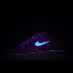 Purple Nike Air Force 1 sneakers with blue swoosh under dark lighting