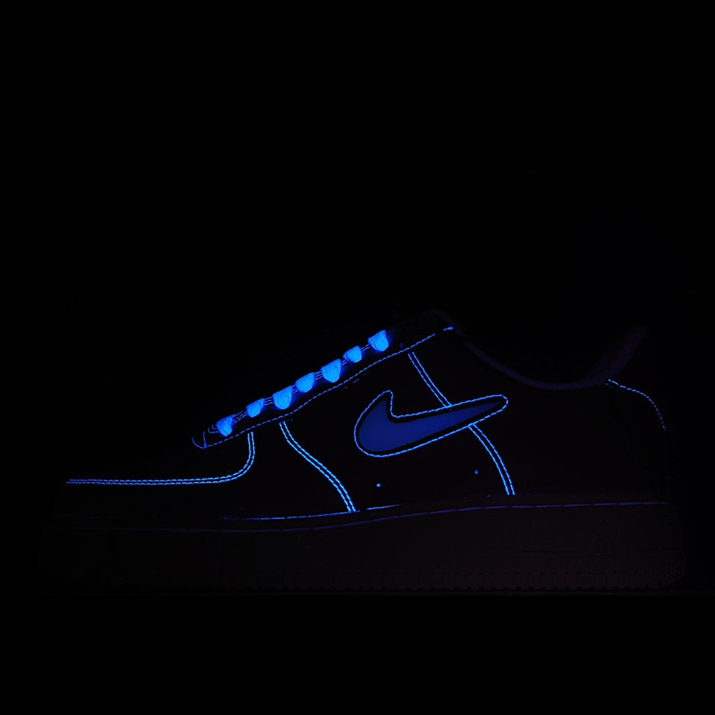 Dark-lit low-top sneaker with blue glowing swoosh and laces