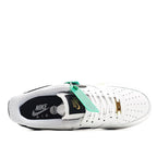 White sneaker with black collar panel, gold lace eyelets, and green tag