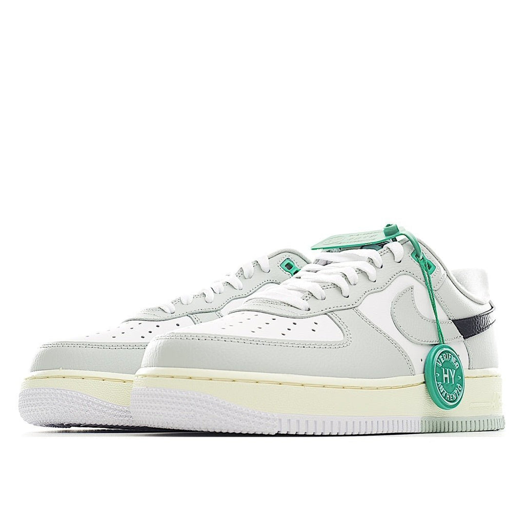 White Air Force 1 low-top with green laces, navy heel stripe, and light gum sole.