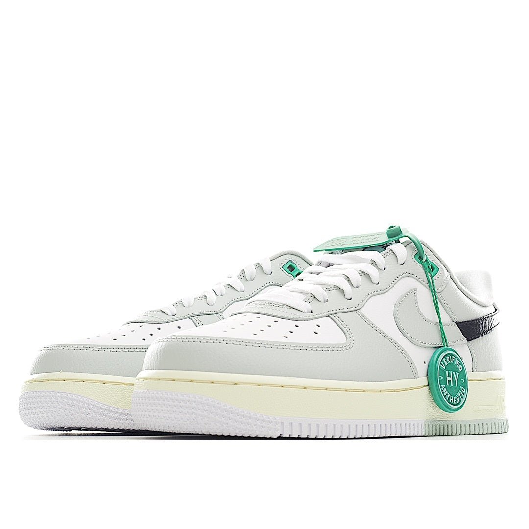White Air Force 1 low-top with green laces, navy heel stripe, and light gum sole.