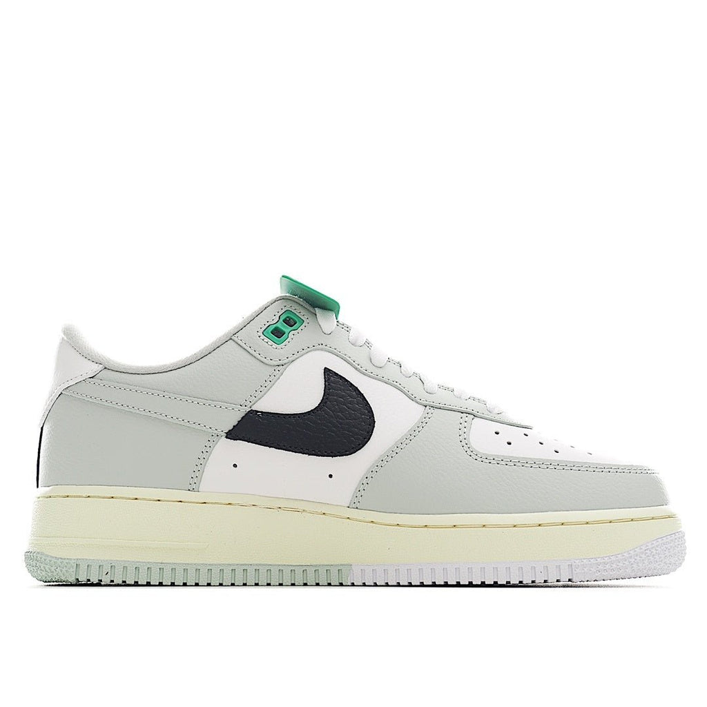 White sneaker with navy swoosh panel, green lace tab, perforated toe, and gum midsole.