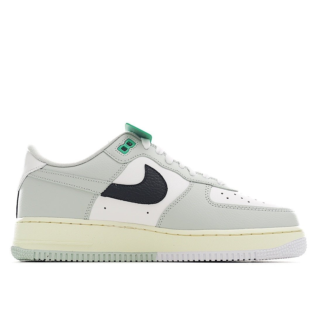 White sneaker with navy swoosh panel, green lace tab, perforated toe, and gum midsole.