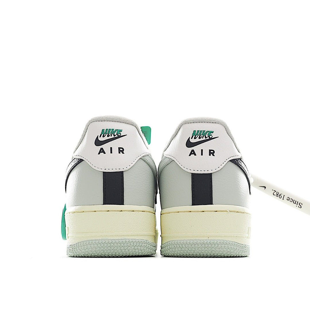 White Air Force 1 heel view with green label, navy center stripe, and light gum sole.