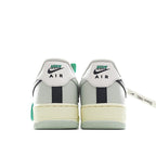 White Air Force 1 heel view with green label, navy center stripe, and light gum sole.