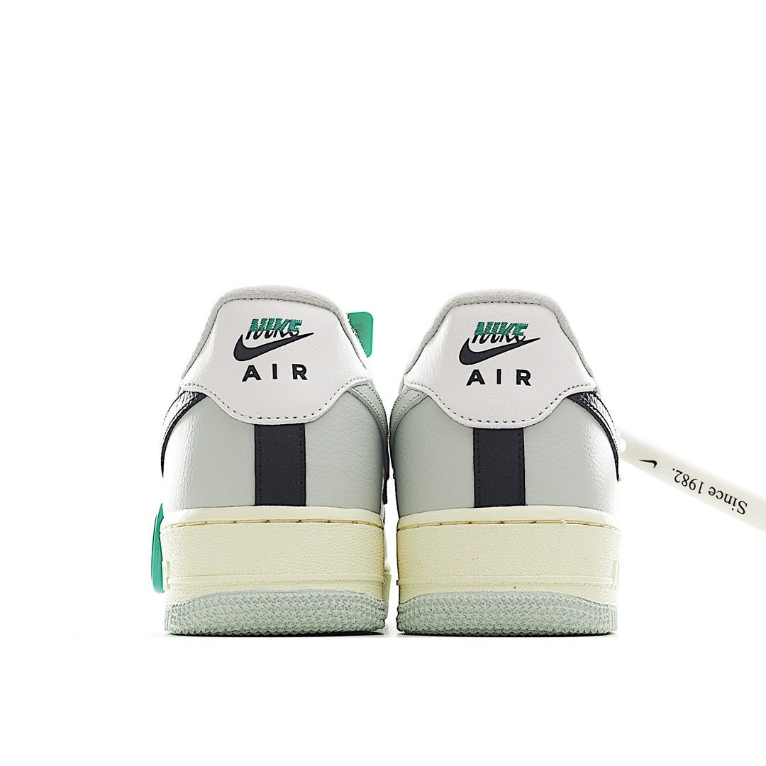 White Air Force 1 heel view with green label, navy center stripe, and light gum sole.