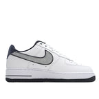 White low-top sneaker with navy heel and black Swoosh, side profile.