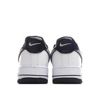 White low-top sneaker pair heel view with navy Nike Swoosh on back.