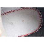 White insole with red stitched perimeter and small tan dot, close-up.