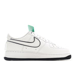 White low-top sneakers with black swoosh and green tongue tag