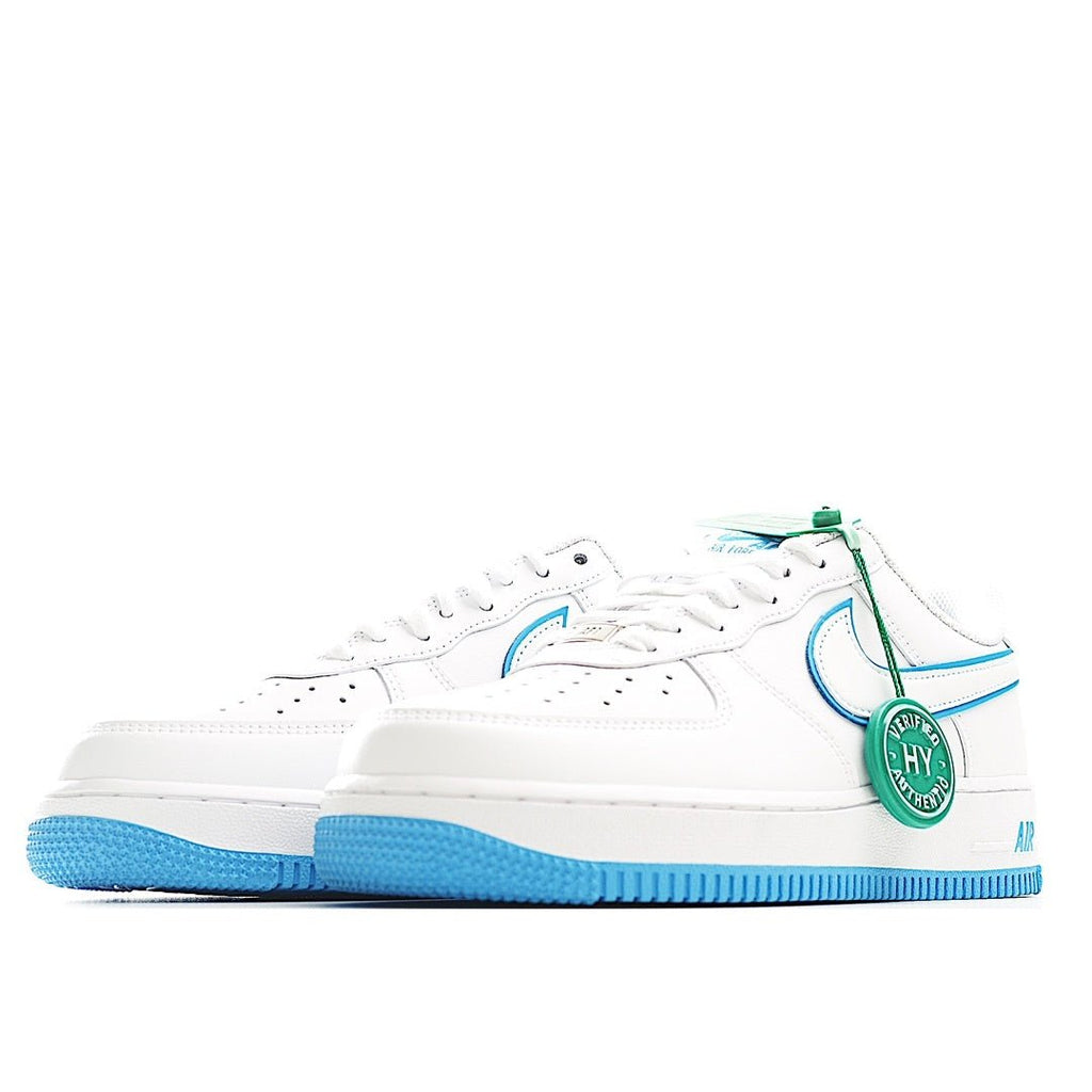 White low-top sneaker side view, blue swoosh and outsole, green lace tag.