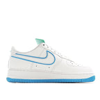 White low-top sneaker with blue swoosh and stripe, green collar tab, lace-up.