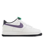 White low-top sneaker with purple swoosh and green lace accent, black rubber outsole