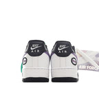 Back view of white low-top sneaker with purple heel accent, green tag, and black sole