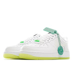 White low-top sneakers with green lace trim, green tag, and neon yellow sole