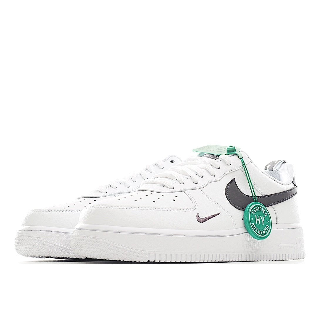 White low-top sneaker with black swoosh and green lace tag detail