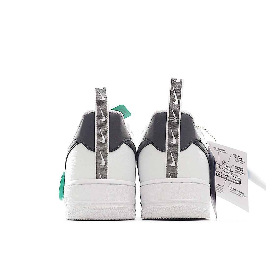 Pair of white sneakers with black heel panels and green pull tab