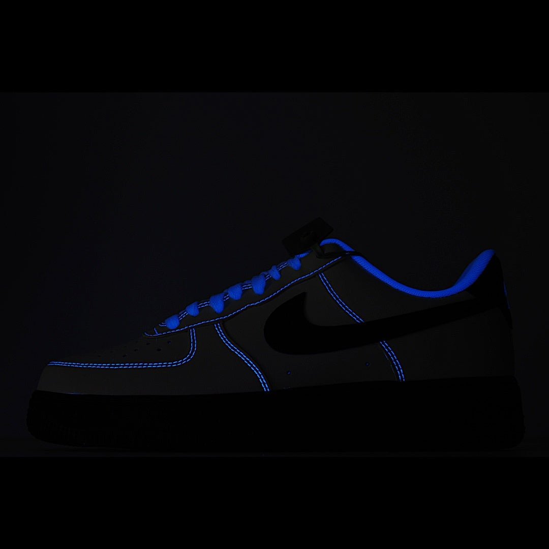 Low-top sneaker in black with blue outline stitching and blue swoosh detail.