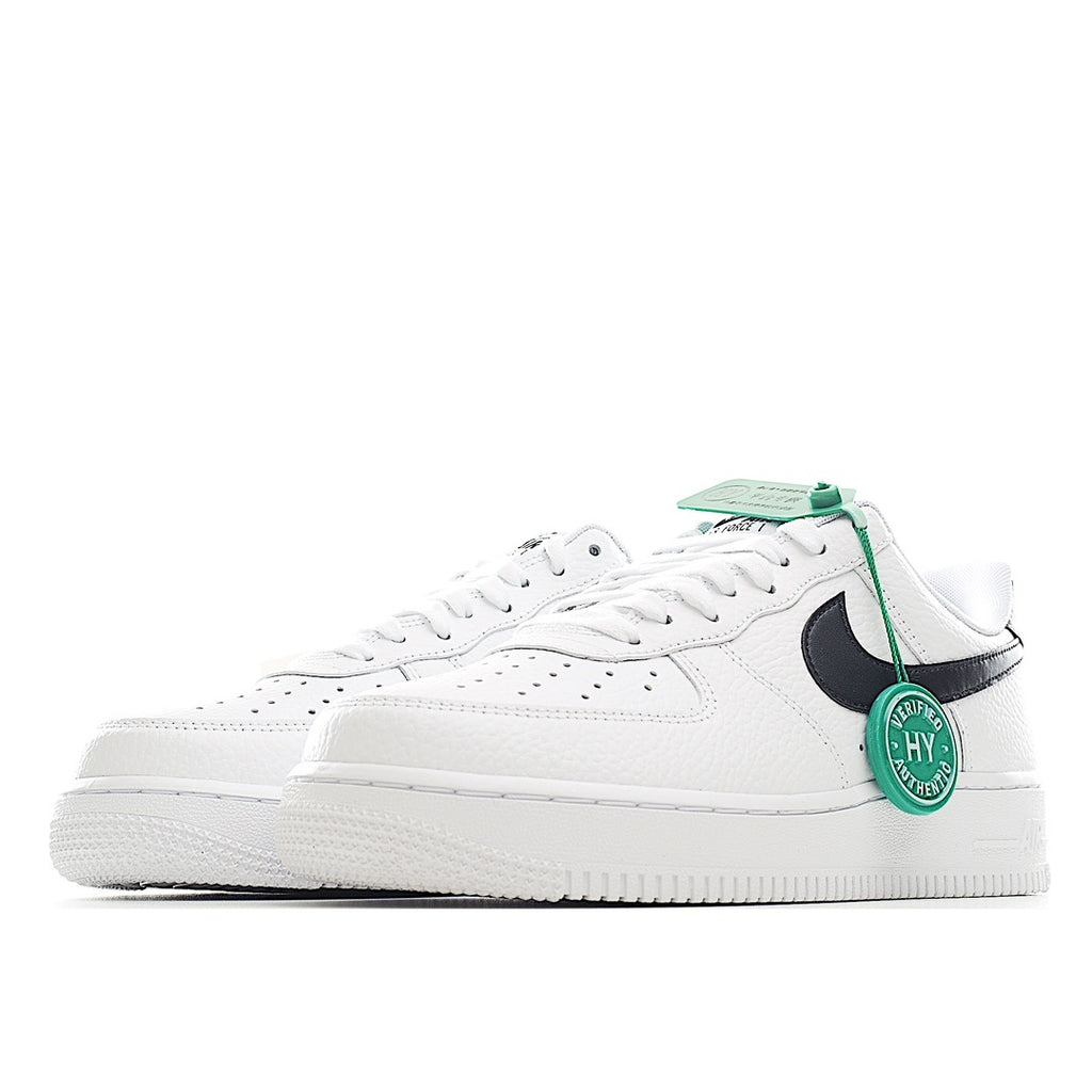 White low-top sneaker with black side swoosh and green lace tag