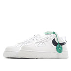 White low-top sneaker with black side swoosh and green lace tag