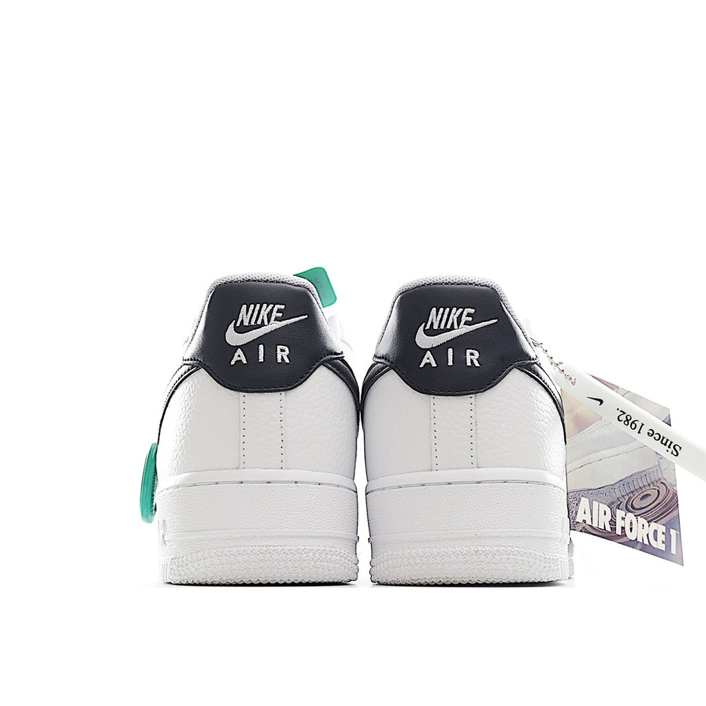 Pair of white sneakers with black heel tabs and green collar accents