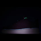 Nike Air Force 1 low-top sneaker in dark lighting, dark upper with green accent and white sole