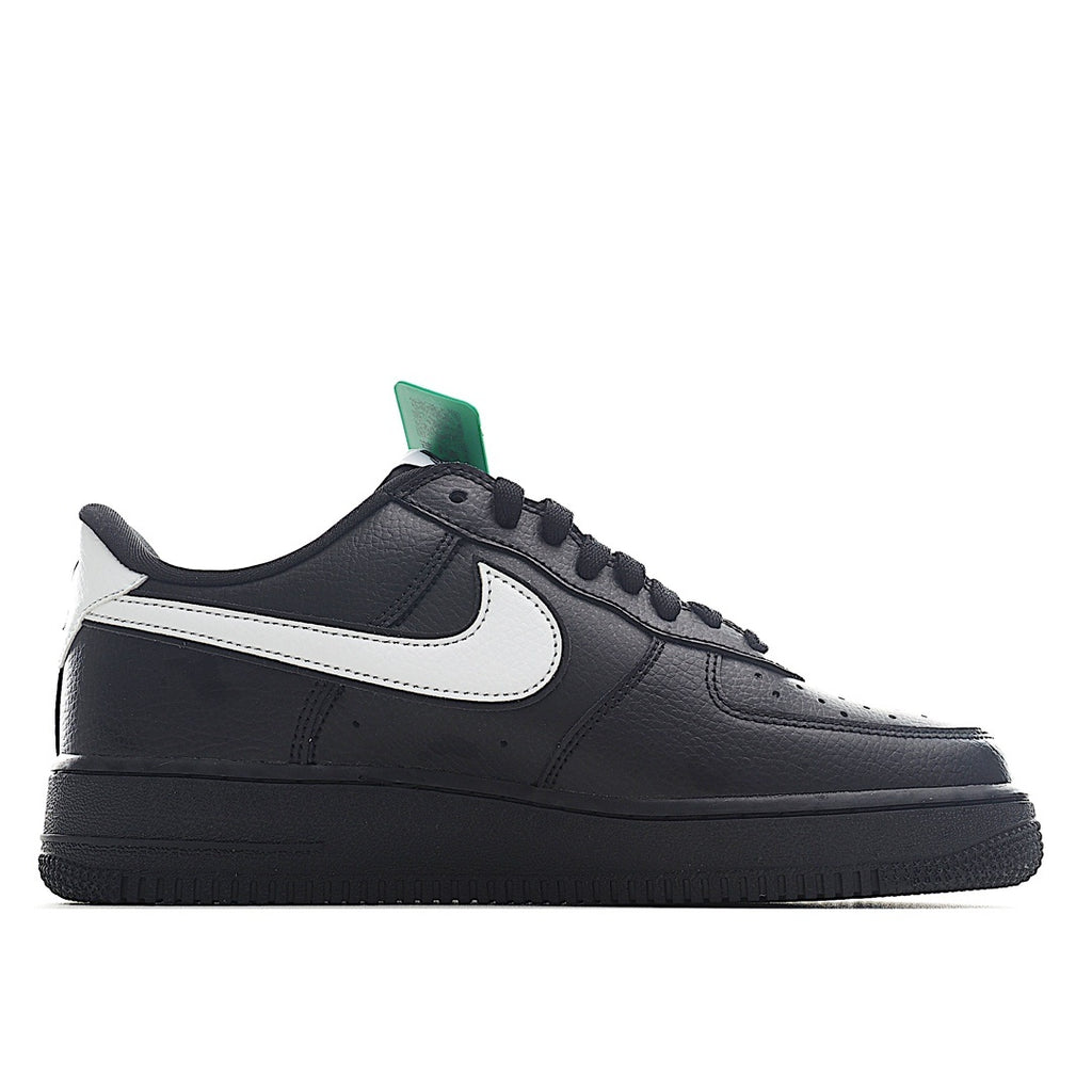Low-top sneakers in black leather with white swoosh and green collar pull tab