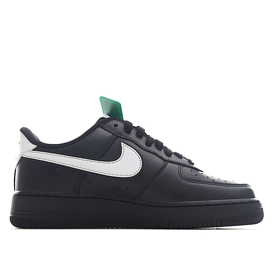 Low-top sneakers in black leather with white swoosh and green collar pull tab