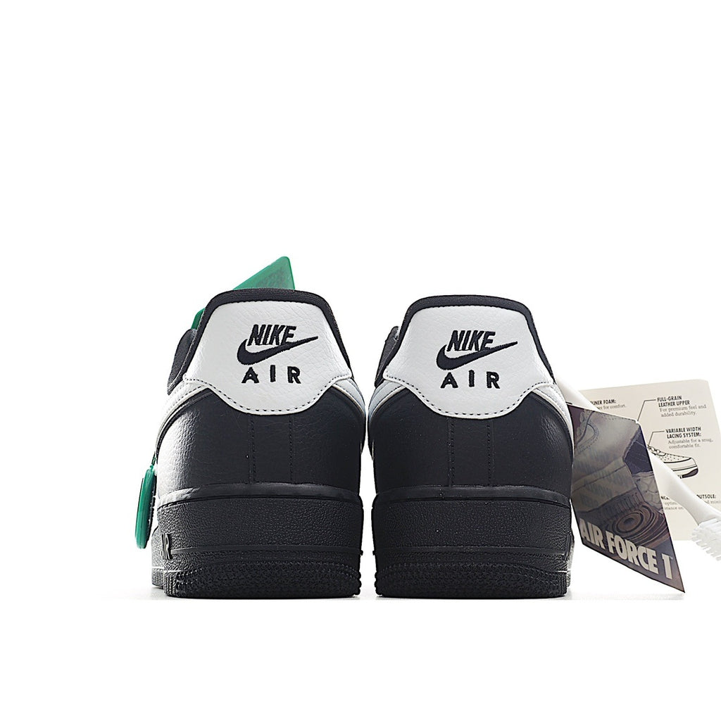 Back view of low-top sneakers with black uppers, white heel tabs, and green accents