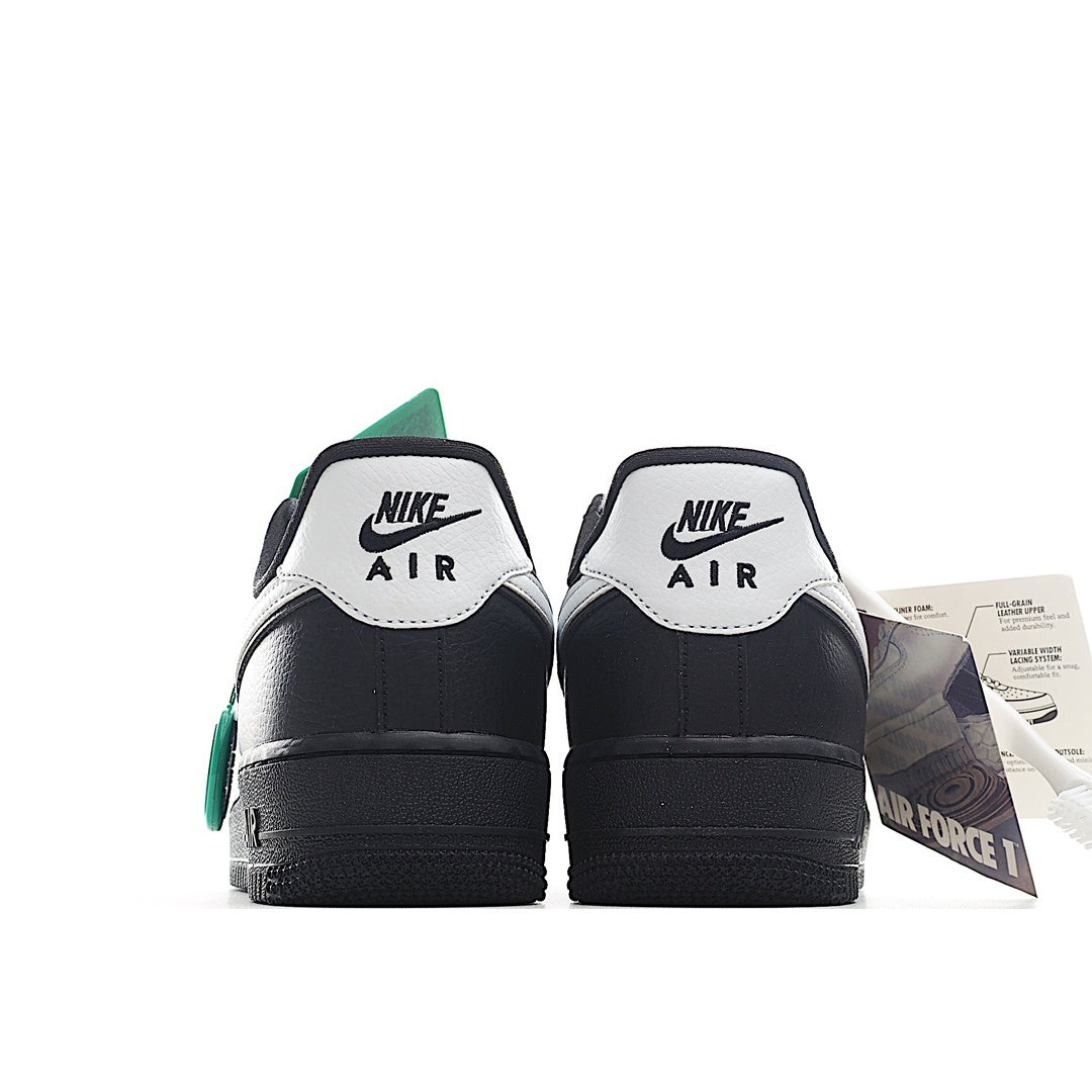 Back view of low-top sneakers with black uppers, white heel tabs, and green accents