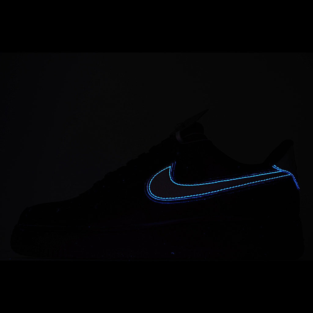 Low-top sneakers in black with blue swoosh outline on a dark background