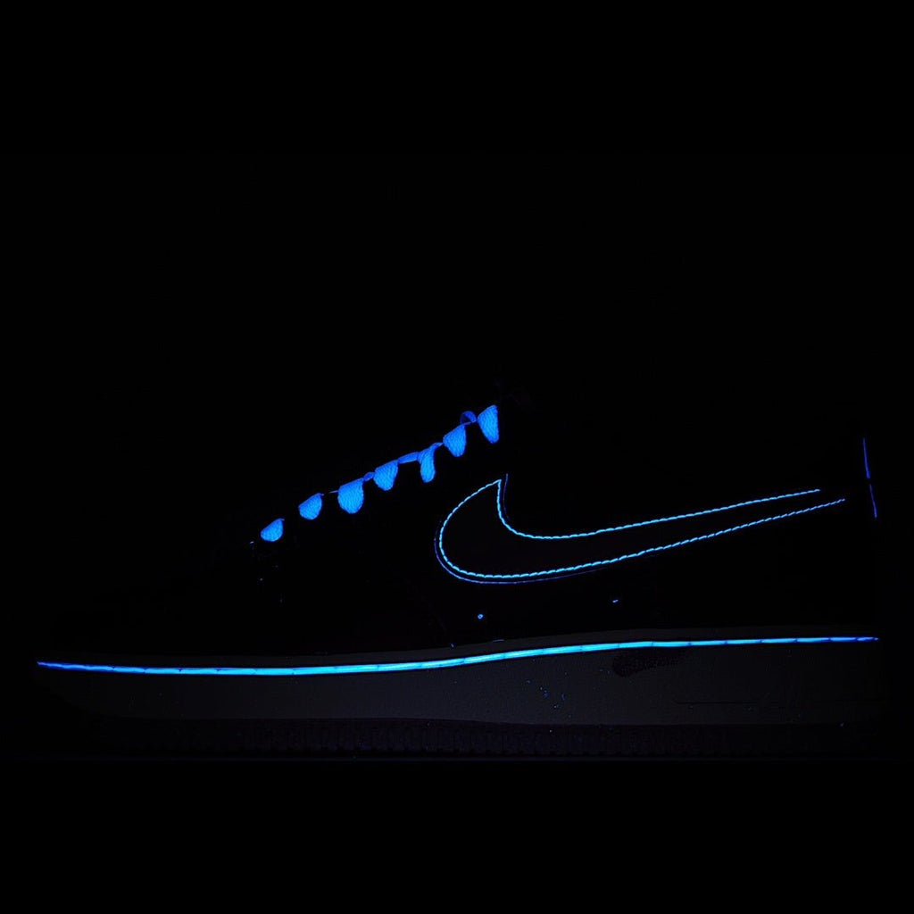 Dark low-top sneaker with glowing blue swoosh detail and blue-tinged laces
