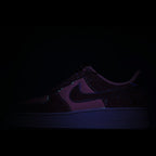 Dark low-top sneaker with purple swoosh and textured midsole detail