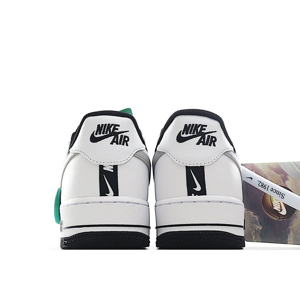 White Nike Air Force 1 sneakers with black heel tabs and green trim.