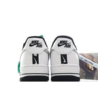 White Nike Air Force 1 sneakers with black heel tabs and green trim.