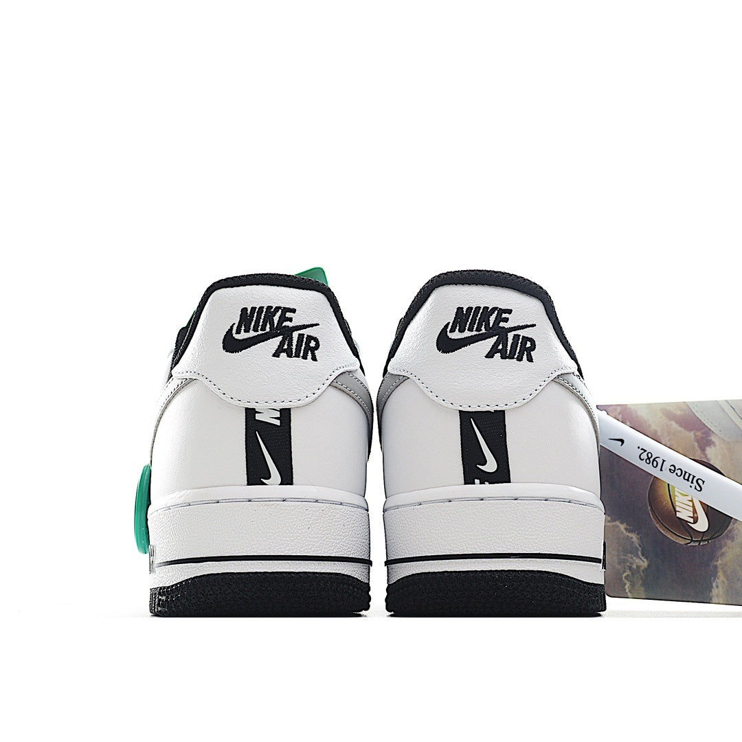 White Nike Air Force 1 sneakers with black heel tabs and green trim.