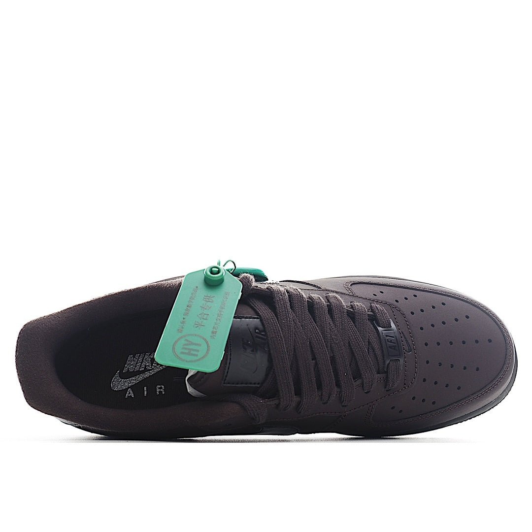 Air Force 1 sneakers, dark colorway with black laces and green hang tag at tongue.