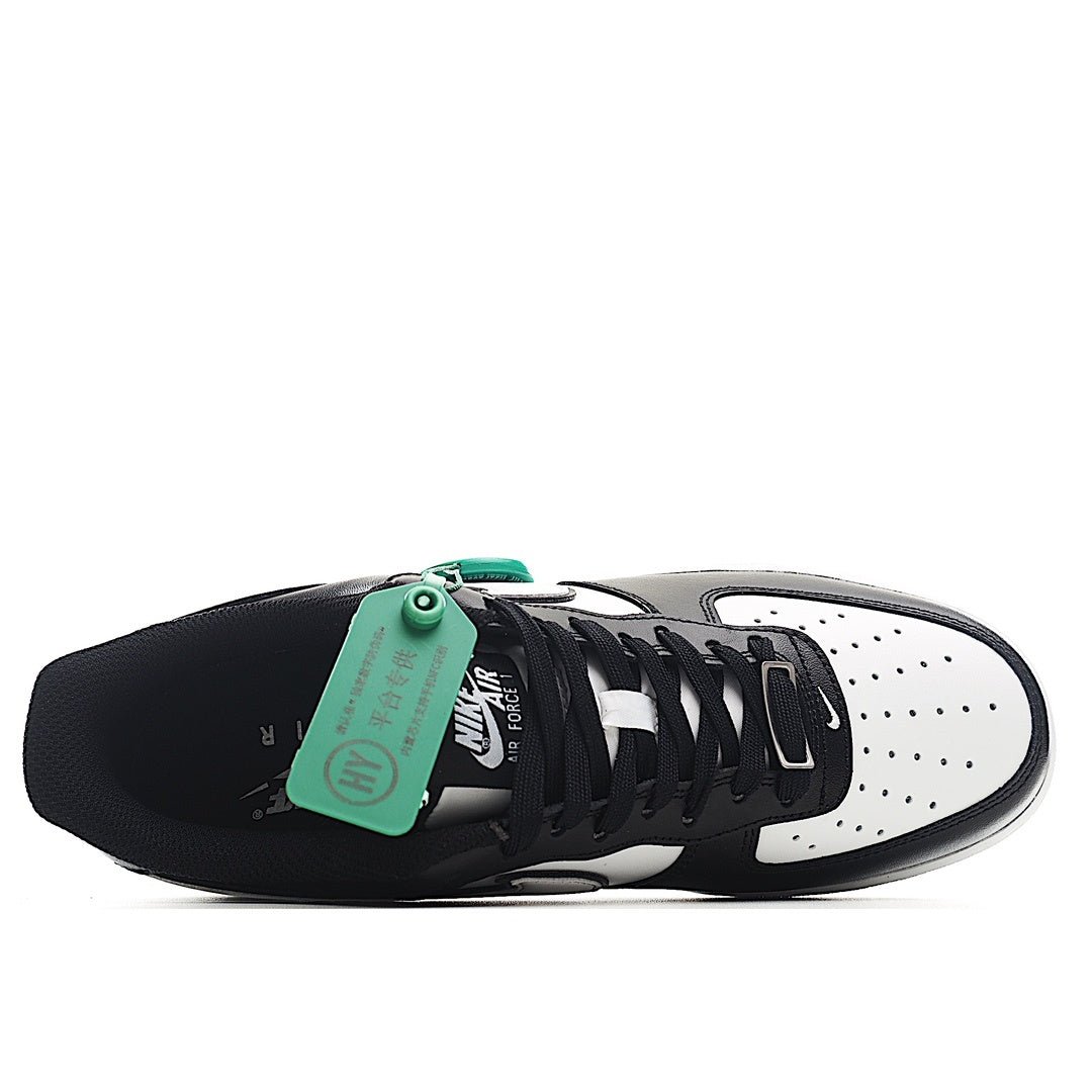 Black-and-white Air Force 1 low-top sneaker with laces and green tag on tongue