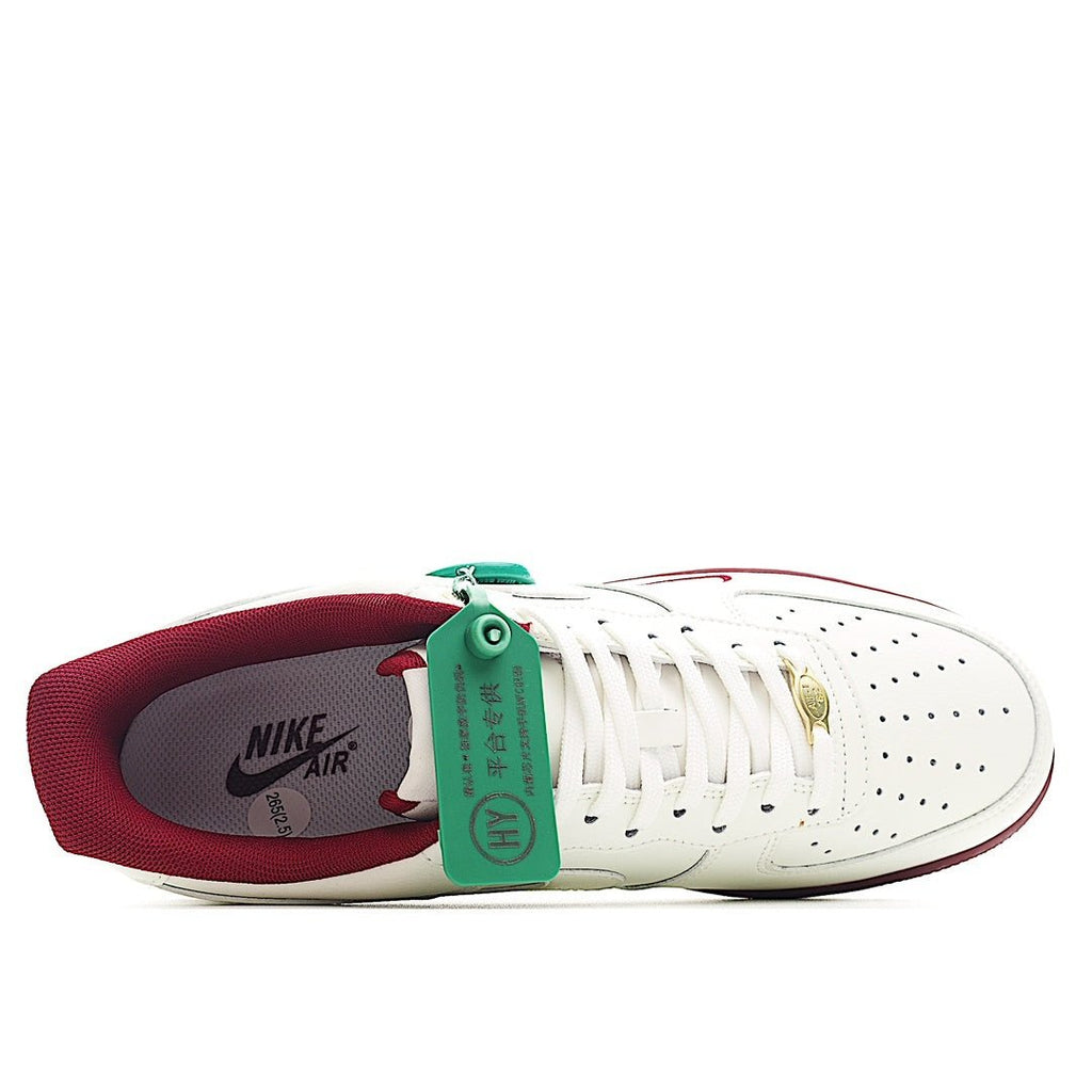 White Air Force 1 sneaker with burgundy lining, green tongue tag, and lace eyelets