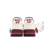 Pair of white Air Force 1 sneakers with burgundy heel panels and red Nike Air text