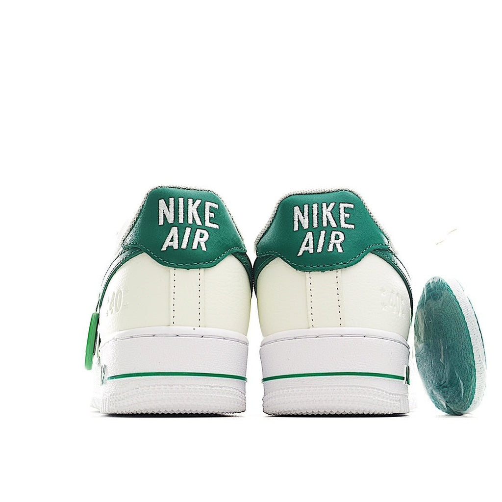 Pair of white low-top sneakers with green heel panels and “NIKE AIR”