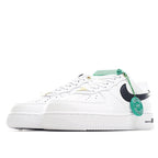 White leather sneaker side view with black swoosh, green laces, and perforated toe