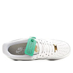 White Nike Air Force 1 sneakers with gray lining and green inner tag over the tongue